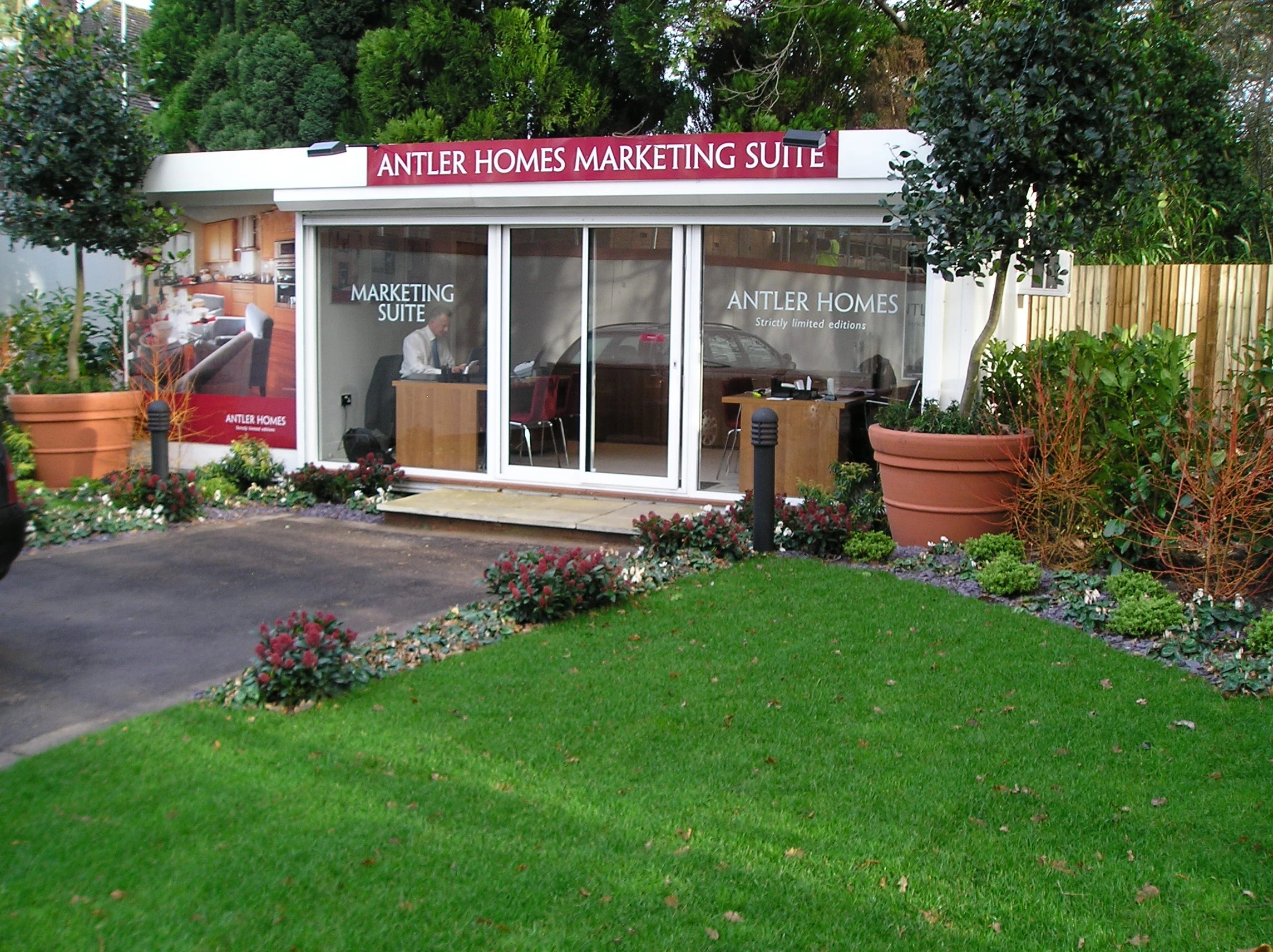 Image shows modular marketing suite for Antler Homes. It is situated in a vibrant garden with lots of flowers